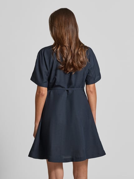 Vrouwenmodel draagt tailliertes Freizeitkleid aus Lyocell-Leinen-Mix Modell 'DALINIA' van BOSS, effen donkerblauw, getailleerde fit, mini-lengte, staande kraag, decoratieve naden, afneembare riem met riemlussen, verborgen knoopsluiting, korte mouwen, rechte zoom, steekzakken, materiaalmix met lyocell en linnen. Volledige lichaamsaanzicht achteraan.