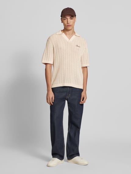 Mężczyzna nosi Slim Fit Poloshirt in Crochet-Optik od REVIEW, beżowa bawełna, krój slim fit, krótki rękaw, logo, przód, zdjęcie całopostaciowe