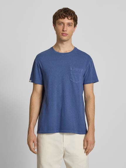 Männermodel trägt T-Shirt aus Baumwoll-Leinen-Mix mit Brusttasche von Superdry in Blau, Regular-Fit, Rundhalsausschnitt, Herren T-Shirt, Rückenlänge bei Größe M 66 cm, Ganzkörperansicht von vorne.