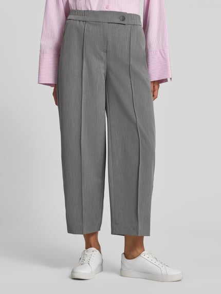 Frauenmodel trägt graue Stoffhose mit Bügelfalte Modell 'Cisilia' von someday, Material-Mix, Barrel Fit, Nahaufnahme Unterkörper.