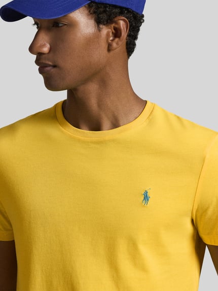 Männermodel trägt Regular Fit T-Shirt aus reiner Baumwolle von Polo Ralph Lauren in Uni-Gelb mit Logo-Stitching, Nahaufnahme Oberkörper.