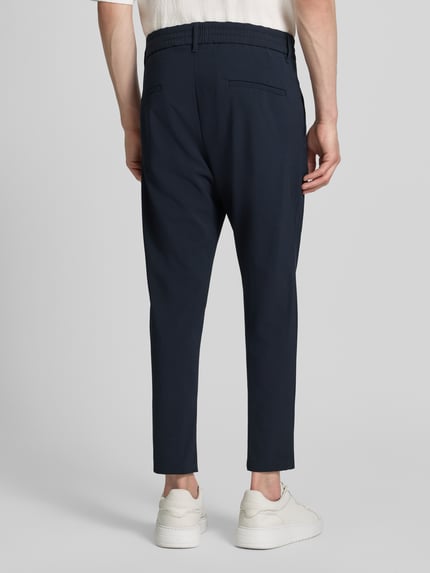 Mannenmodel draagt heren broek met achterzakken model 'CHASY' van Drykorn in donkerblauw materiaalmix met katoen, slim fit, bandwijdte maat 32/32: 33 cm, binnenbeenlengte maat 32/32: 64 cm, geheelopname achteraan.