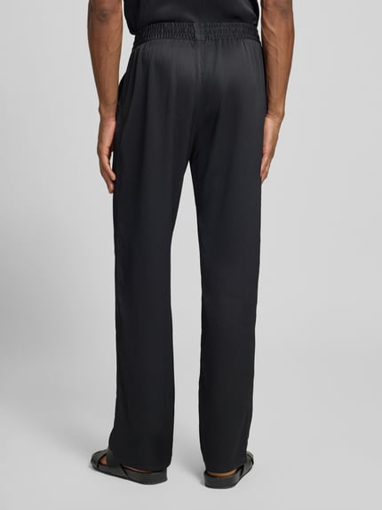 Männermodel trägt Hose mit elastischem Bund Modell 'Houston' von Les Deux, plissiertes Material, Loose-Fit, Ganzkörperansicht Rückansicht.