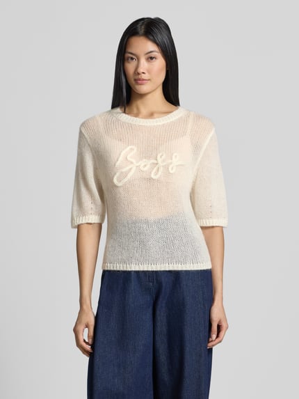 Frauenmodel trägt cremefarbenen, halbtransparenten Regular Fit Pullover aus Schurwoll-Modal-Mix Modell 'C_Farezza' von BOSS Orange, lockere Strickstruktur, Ganzkörperansicht von vorne.