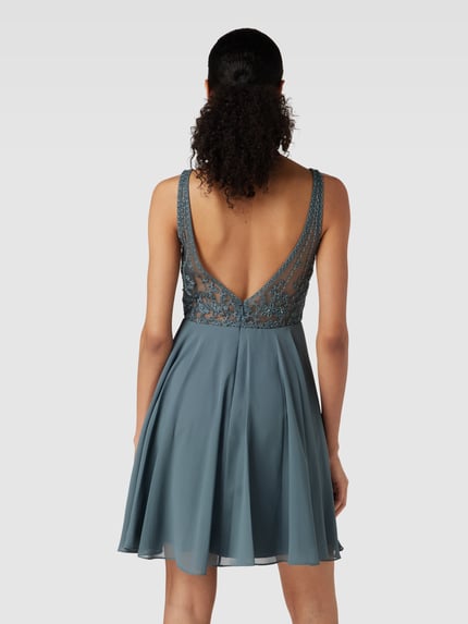 Frauenmodel trägt Regular fit Minikleid mit floralem Spitzenbesatz von Laona, semitransparente Optik, Ziersteinbesatz, ärmelloses Design, blickdichter Unterrock, florale Textur, Rückansicht Ganzkörperansicht.