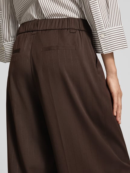 Kobieta nosi Regular Fit Gerade Hose mit Viskose-Anteil Modell 'Moira Bloom' von OPUS PANTS, brązowy kolor, delikatny połysk, widoczna tekstura, detal tylny pas, detalaufnahme.