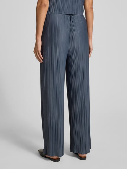 Frauenmodel trägt Wide Fit Stoffhose in Plissee-Optik Modell 'Uma' von Samsøe Samsøe, Elastischer-Material-Mix, Ganzkörperansicht Rückansicht.