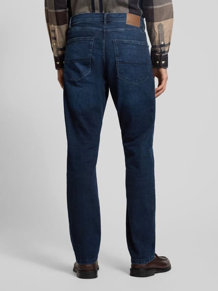 Männermodel trägt Regular Fit Jeans im Used-Look von Christian Berg Men aus dunkelblauem Baumwoll-Mix mit Eingrifftaschen, Ganzkörperansicht Rückansicht. Bundweite 43 cm, Innenbeinlänge 83 cm bei Größe 32/32, Stretch-Anteil.