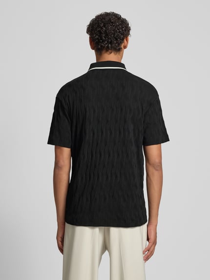 Männermodel trägt Regular Fit Poloshirt aus reiner Baumwolle Modell 'DUNIK' von HUGO in Schwarz mit strukturierter Allover-Optik, Ganzkörperansicht Rückansicht.