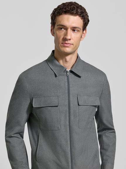 Männermodel trägt Blouson mit Zweiwege-Reißverschluss von CINQUE in Grau, glatte Struktur, Kentkragen, Pattentaschen, Nahaufnahme Oberkörper.