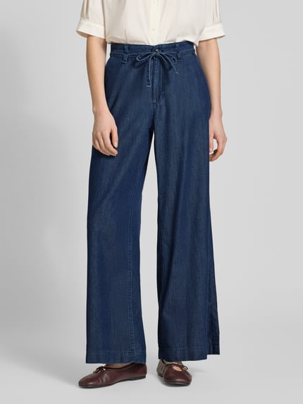 Frauenmodel trägt Wide Leg Jeans mit Bindegürtel Modell 'Wendy' von MAC aus Baumwoll-Lyocell-Mix in Dunkelblau, Ganzkörperansicht von vorne.