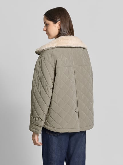Frauenmodel trägt Steppjacke mit herausnehmbarer Kapuze Modell 'HENRIKE' von Blonde No. 8 in Beige mit Kunstfellfutter, Ganzkörperansicht Rückansicht.