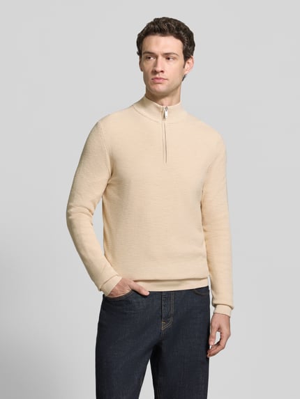 Männermodel trägt Slim Fit Strickpullover aus Baumwoll-Mix mit Troyer-Kragen von Profuomo in Beige, Struktur glatt, Ganzkörperansicht von vorne. Rückenlänge 69 cm, Ärmellänge 70 cm, elastische Abschlüsse.