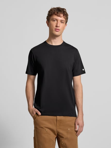 Männermodel trägt schwarzes T-Shirt mit geripptem Rundhalsausschnitt von Carhartt Work In Progress, reine Baumwolle, Regular Fit, Ganzkörperansicht von vorne.