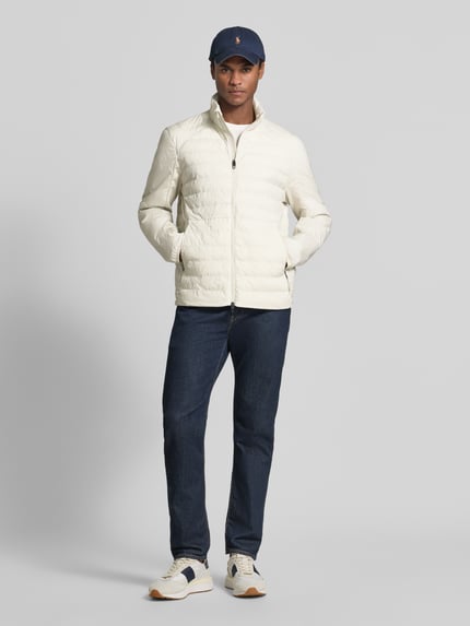 Männermodel trägt Regular Fit Sweatjacke mit Steppdetails von Polo Ralph Lauren in Creme zu dunkler Jeans, Ganzkörperansicht von vorne.