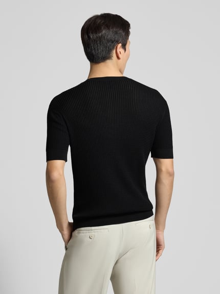 Männermodel trägt Slim Fit T-Shirt mit Seiden-Anteil in Strick-Optik von Emporio Armani, Schwarz, elastische Abschlüsse, Ganzkörperansicht Rückansicht.