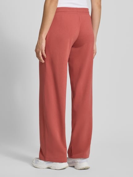 Frauenmodel trägt Sweatpants mit Tunnelzug von REVIEW in Ziegelrot, Baumwoll-Mix, Gerader-Schnitt, elastischer Bund, Ganzkörperansicht Rückansicht.