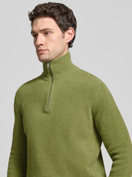 Männermodel trägt Pullover mit Troyerkragen von MARC O'POLO in Grün, Regular Fit, Strukturstrick, mit Reißverschluss und Rippbündchen, Nahaufnahme Oberkörper.