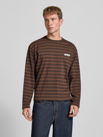 Männermodel trägt Gestreiftes Langarmshirt mit Logoprint vorne und hinten von REVIEW, braune und dunkelbraune Streifen, reine Baumwolle, Regular Fit, Rundhalsausschnitt, Ganzkörperansicht von vorne.