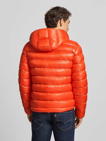 Männermodel trägt rote Steppjacke mit Kapuze und Zweiwege-Reißverschluss Modell 'ADAMS' von Blauer USA, Ganzkörperansicht Rückansicht. Regular Fit, sichtbare Steppnähte, glatte Textur.