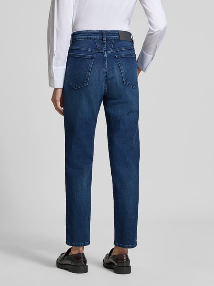 Männermodel trägt Straight Fit Jeans aus Mieszanka bawełny marki Closed Modell 'PEDAL PUSHER', kolor ciemnoniebieski, kieszenie z tyłu, skrócony krój, zapięcie na guzik i zamek błyskawiczny, nadruk z napisem, szerokość w rozmiarze 27/32: 33 cm, długość wewnętrzna nogawki w rozmiarze 27/32: 69 cm. Ganzkörperansicht Rückansicht.