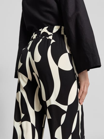 Frauenmodel trägt Stoffhose aus Viskose im Allover-Look Modell 'CHANISE' von Soyaconcept, Relaxed-Fit, Ganzkörperansicht Rückansicht. Bundweite 35 cm, Innenbeinlänge 76 cm bei Größe S.