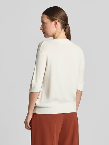 Frauenmodel trägt Strickpullover aus Viskose-Mix von MORE & MORE in Creme mit gerippten Abschlüssen, taillierte Passform, Ganzkörperansicht Rückansicht.