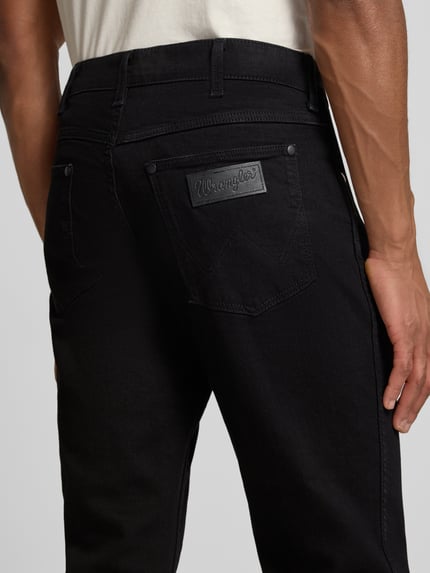 Männermodel trägt Straight Fit Jeans im 5-Pocket-Design Modell 'Greensboro' von Wrangler, zwart, katoenmengsel met stretch, detailopname rugaanzicht.