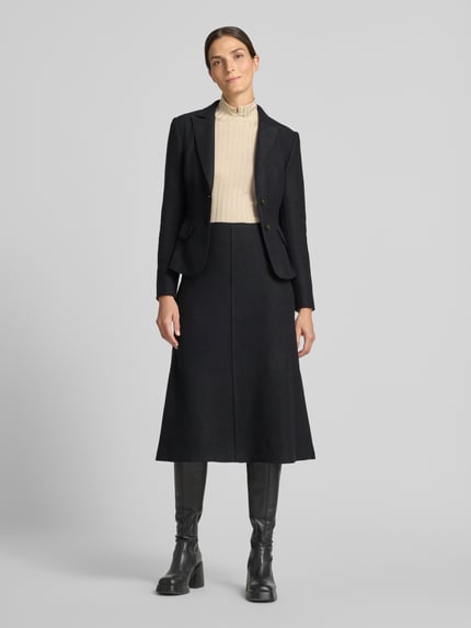 Frauenmodel trägt Midirock aus Schurwolle mit Reißverschluss von Marc Cain, schwarz, A-Linie, Teilungsnaht, Label-Detail, Ganzkörperansicht von vorne.