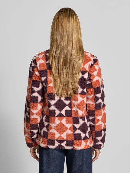 Vrouwenmodel draagt Regular Fit Jacke mit Stehkragen van Columbia in fleece met oranje, paarse en roze geometrische vlakken, lange mouwen, rechte zoom, Napoleon- en steekzakken, ritssluiting, ruglengte 61 cm, schouderbreedte 39 cm, borstwijdte 49 cm, mouwlengte 63 cm, volledige rugaanzicht.
