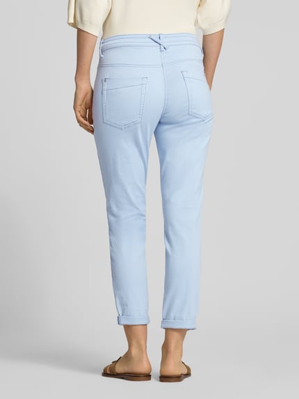 Frauenmodel trägt Tapered Fit Chino aus Baumwoll-Mix von Tom Tailor, Optik: Unifarben, Passform: Tapered-Fit, Low Waist, Cropped, 5-Pocket-Design, Label-Prägung, Webstruktur, Farbe Hellblau, Ganzkörperansicht Rückansicht.