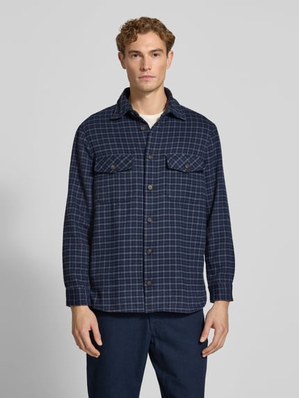 Männermodel trägt Regular Fit Overshirt mit Karo-Muster von Christian Berg Men in Dunkelblau mit Knopfleiste, Ganzkörperansicht von vorne. Herren Freizeithemd