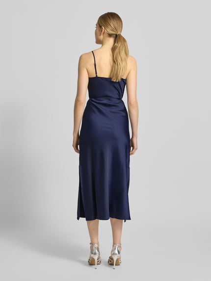 Männermodel trägt Slim Fit Midikleid aus Satin Modell 'Thea' von YAS in dunkelblau, elastyczna mieszanka materiałów, cienkie ramiączka, odpinana tasiemka w talii, długość tyłu w rozmiarze 36: 124 cm, szerokość w rozmiarze 36: 46 cm, satynowa powierzchnia, Ganzkörperansicht Rückansicht