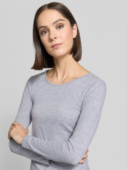 Frauenmodel trägt Longsleeve mit Rundhalsausschnitt von ZABAIONE in Hellgrau, taillierter Schnitt, glatte Textur, Nahaufnahme Oberkörper. Baumwoll-Elasthan-Mix, Rückenlänge bei Größe S: 55 cm.