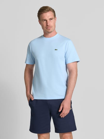 Männermodel trägt Regular Fit T-Shirt aus reiner Baumwolle von Lacoste in Hellblau, weiche Textur, Herren T-Shirt, Ganzkörperansicht von vorne.