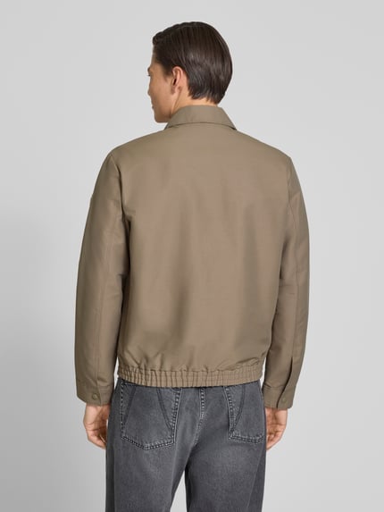 Männermodel trägt Regular Fit Blouson mit elastischem bund van Marc O'Polo, look: effen, regular fit pasvorm, platte kraag, ritssluiting, labelpatch, lange mouw met drukknoop, elastische rompzoom, zij-steekzakken, binnenzak, Ganzkörperansicht Rückansicht.