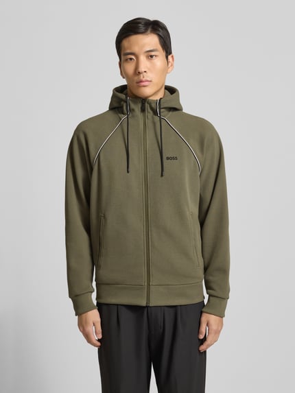 Männermodel trägt Regular Fit Sweatjacke aus Baumwoll-Mix von BOSS Green, oliv, Kapuze, Reißverschluss, Kontraststreifen, Ganzkörperansicht von vorne.