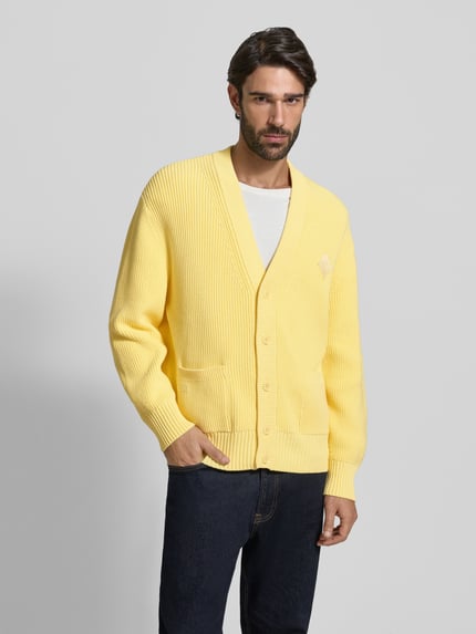 Männermodel draagt Relaxed Fit Gebreid jack uit katoenmix Model 'COTES PERLEES' van Lacoste, look: effen, knoopsluiting, labelopschrift, labelstitching, lange mouw, geribde rompzoom, materiaalverwerking: knitwear, kleur: geel. Ganzkörperansicht van voren.