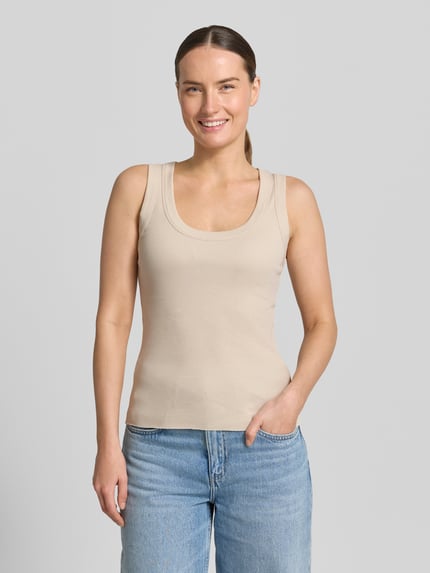 Modelka kobieca ma na sobie Tanktop z okrągłym dekoltem model 'TAVIRA' od Drykorn, beżowy, wykonany z czystej bawełny, krój slim fit, dzianina o drobnym prążku, długość pleców w rozmiarze S: 41 cm, widok całej sylwetki z przodu.