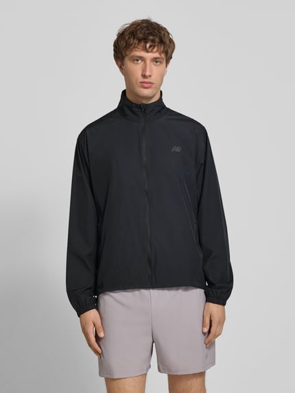Männermodel trägt Regular Fit Jacke in Stehkragen Modell 'Fast Days' von New Balance, schwarz, Reißverschlusstaschen, Ganzkörperansicht von vorne.