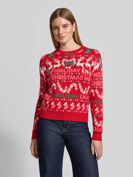 Frauenmodel trägt Pullover mit Weihnachtsmotiv-Frontprint von VERO MODA, mehrfarbiges Allover-Muster, Strickoptik, Nahaufnahme Oberkörper.