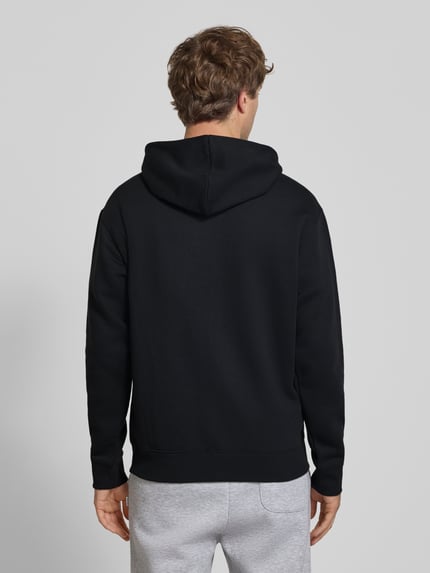 Männermodel trägt Sweatjacke mit Känguru-Tasche und Label-Stitching von New Balance aus schwarzem Baumwoll-Mix, Ganzkörperansicht Rückansicht.