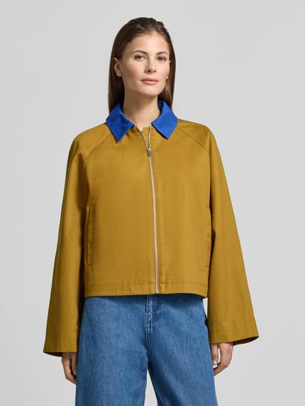 Frauenmodel trägt Kurze Barn-Jacket mit Kontrast-Kragen - curated by Tinvcb von SIC, relaxed Fit, reine Baumwolle, Umlegekragen in Gelb mit blauem Kragen, Reißverschluss, kombiniert zu blauer Jeans, glatte Textur, Ganzkörperansicht von vorne.