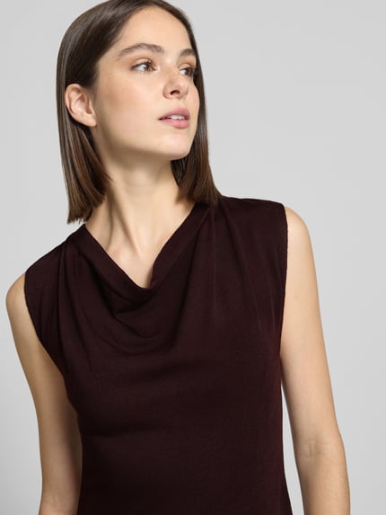 Frauenmodel trägt Strickkleid mit Wasserfall-Ausschnitt Modell 'SANTA' von MANGO in Dunkelbraun, feine Struktur, Nahaufnahme Oberkörper.