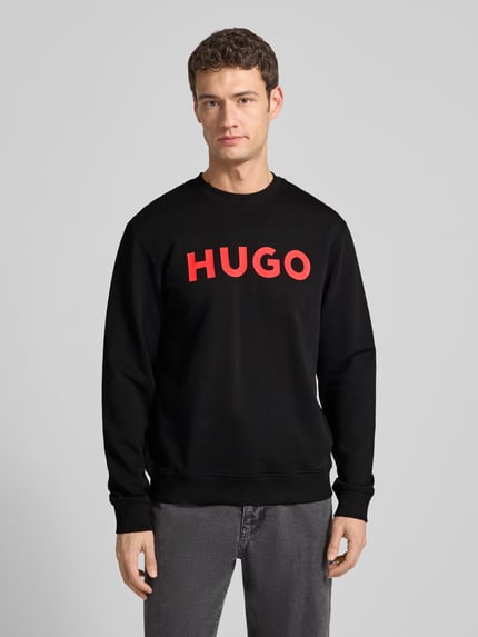 Männermodel trägt Sweatshirt mit Label-Detail Modell 'Dem' von HUGO in Schwarz, reine Baumwolle, lockere Passform, Ganzkörperansicht von vorne.