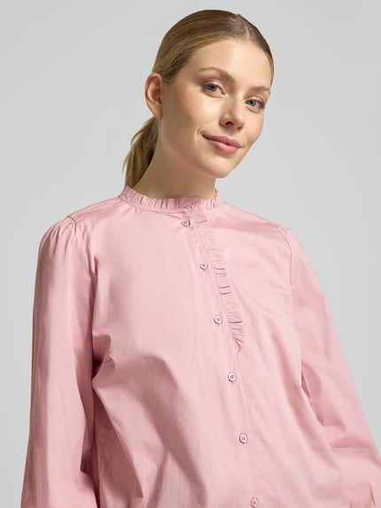 Frauenmodel trägt Bluse mit Rüschenkragen und abgerundetem Saum von MORE & MORE in Rosa, Baumwoll-Mix mit Stretch, Nahaufnahme Oberkörper.
