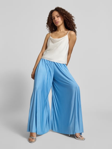 Vrouwenmodel draagt Stoffhose mit Plisseefalten Modell 'Samantha' van GUIDO MARIA KRETSCHMER WOMAN, satijn, wide leg fit, elastische tailleband, lichtblauw met subtiele plooien, binnenbeenlengte 74 cm bij maat 36, bundwijdte 35 cm bij maat 36. Volledige lichaamsweergave van voren.