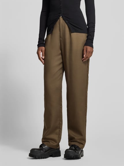 Frauenmodel trägt Straight Fit Chino mit Kellerfalten von black palms in Braun, seitliche Eingrifftaschen, glatte Textur, Nahaufnahme Unterkörper.