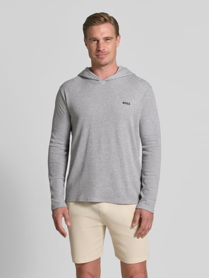 Männermodel trägt Regular Fit Hoodie aus Baumwoll-Mix von BOSS in Hellgrau, glatte Textur, dezentes Logo, Ganzkörperansicht von vorne.