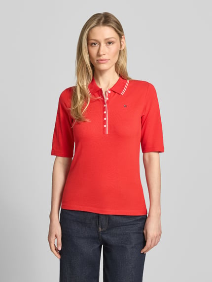 Vrouwenmodel draagt Slim Fit Poloshirt uit Lyocell-mix van Tommy Hilfiger, effen rood, korte knoopsluiting, logo, piqué materiaal. Vooraanzicht busteshot.